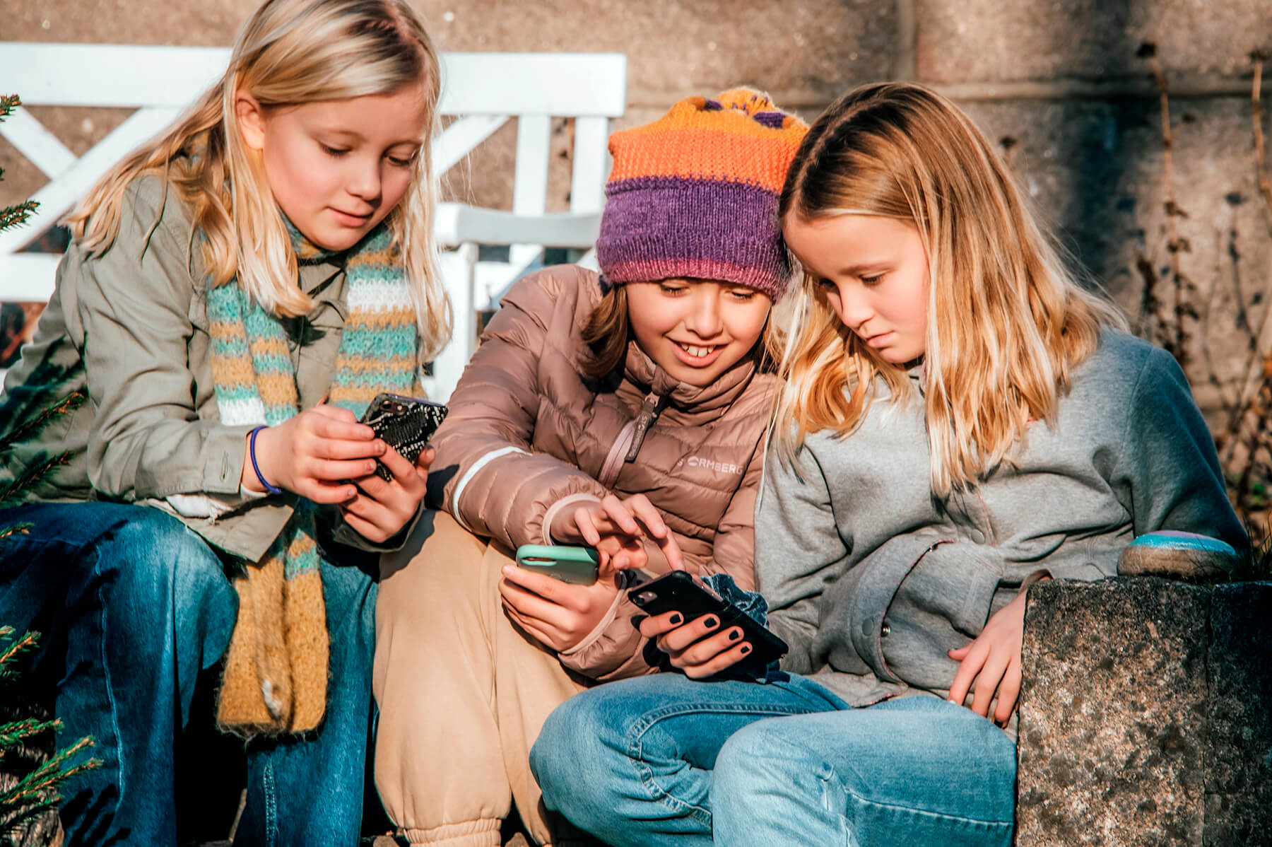 3 barn som er ute og leker med mobiltelefon