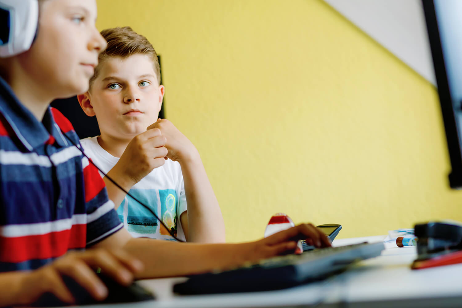 2 gutter sitter sammen foran en datamaskin i et klasserom