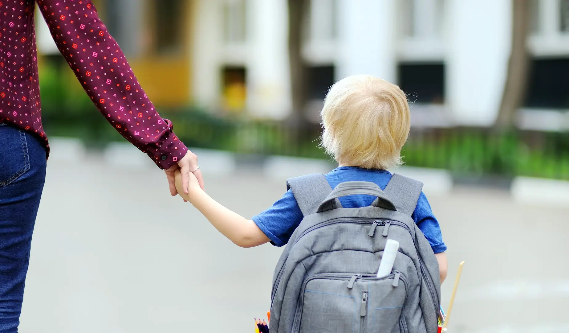 Liten gutt med sekk som leier mammaen sin til skolen