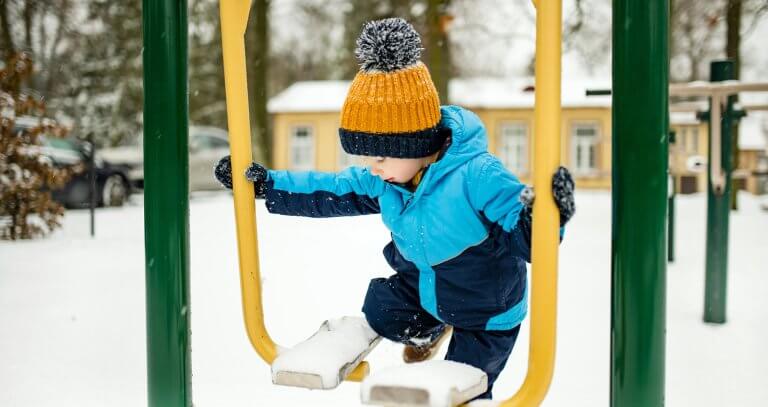 Liten gutt som leker i et lekeapperat ute om vinteren