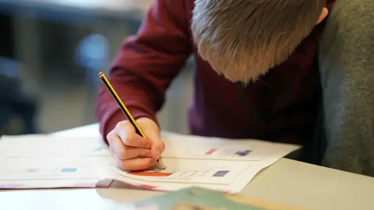barneskole klasse gutt som loser oppgaver visuelt med blyant og tegneblokk