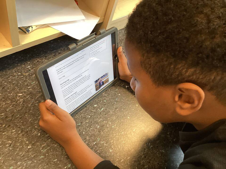 Samir Yasmin Samale fra 6B på Langhus skole har lagt seg på gulvet i klasserommet for å lese i Lille norske leksikon Store norske leksikon