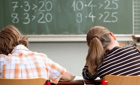 klasserom og tavle med tall 2 barneskole elever jobber med mate