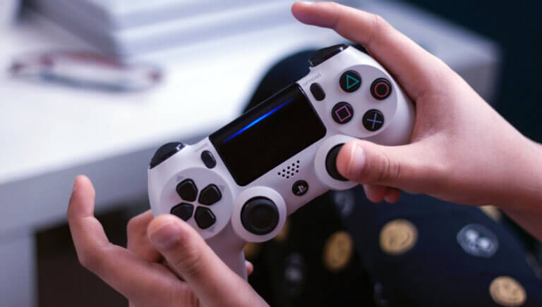 Nærbilde av hender som spiller på en Playstation kontroll