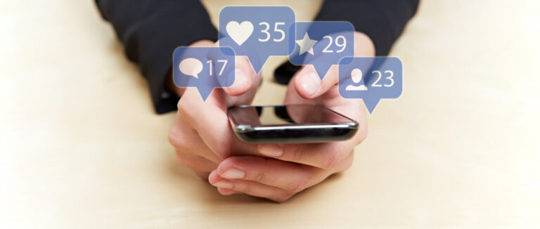 Hender som holder en mobiltelefon som illustrer sosiale medier og likes